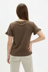 Remera blanca de algodón, de corte ajustado, con cuello redondo y mangas cortas terminadas con volados delicados.