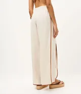 Pantalón largo tipo palazzo de color beige, confeccionado en mezcla de viscosa y lino. Presenta tiro alto, cintura elastizada en la parte posterior y aberturas frontales en las piernas con ribetes en tono marrón contrastante.
