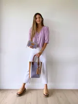 Bolso tipo tote de cuero color lila con textura croco, detalles en cuero marrón y laterales con franjas blancas. Incluye manijas de cuero marrón y accesorio de borlas colgantes.