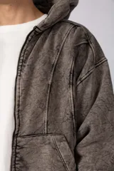 Campera oversize con capucha y cierre frontal, confeccionada en tela con acabado acid wash que le otorga un aspecto desgastado. Presenta costuras curvas decorativas en el frente y la espalda, puños y ruedo acanalados, y un calce relajado.