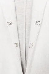 Blazer de textura suave, cuello redondo y manga larga. Presenta un diseño minimalista con cierre frontal mediante un cinturón fino de cuero con hebilla metálica.