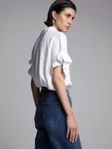 Camisa blanca de lino con cuello clásico, mangas cortas con volados y cierre frontal con botones.