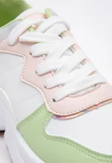 Zapatillas blancas de símil cuero acordonadas con cortes irregulares y pequeños detalles iridiscentes. Su plataforma es irregular y cuenta con 5 cm de alto.