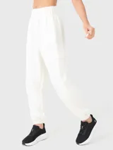 Pantalón de buzo blanco hueso de tela suave, con bolsillos laterales y traseros, y elástico en los tobillos.