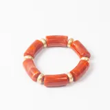 Brazalete elástico compuesto por cuentas cilíndricas de resina en color naranja marmolado intercaladas con esferas metálicas doradas.
