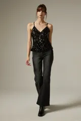 Top de breteles finos con escote en V, confeccionado en tela con lentejuelas y detalles de encaje lateral, con diseño al cuerpo.