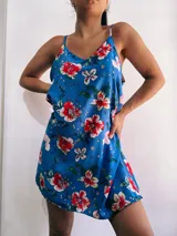 Vestido corto con estampado floral en tonos rojos, blancos y verdes sobre fondo azul.
