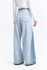 Jean de tiro alto con corte super oxford y silueta amplia. Presenta un diseño bicolor con paneles en diferentes tonos de azul y ruedo desflecado.