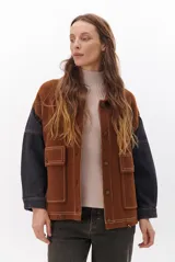 Campera color caramelo con mangas de denim azul oscuro. Presenta cuello alto, cierre frontal con botones, cuatro bolsillos delanteros con solapa y pespuntes blancos decorativos.