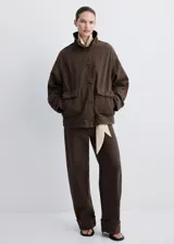 Chaqueta de algodón estilo tejano vaquero, color marrón, de diseño oversize con cuello alto, manga larga, bolsillos delanteros de parche y solapa, y cierre frontal con botones.