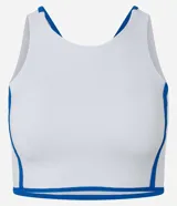Top deportivo femenino confeccionado en microfibra, de color blanco con vivos en azul, escote redondo, copa y breteles anchos.