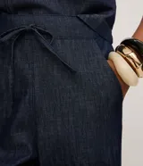 Pantalón de jeans de color azul oscuro, corte carrot (holgado en cadera y afunilado en pierna), con cintura alta ajustable mediante cordón.