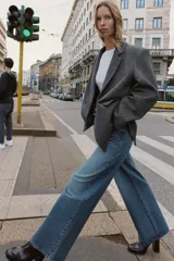 Blazer de corte oversize en color gris jaspeado, con cuello solapa, hombreras y cierre frontal cruzado con botones. Cuenta con bolsillos delanteros con solapa.
