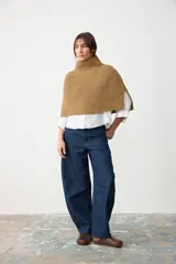 Capita de punto acanalado en color beige, con cuello alto y diseño abierto en los laterales.