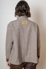 Campera de paño de lana color marrón con diseño oversize. Presenta cuello alto, cierre frontal con botones y detalles en pana azul marino en los puños y en las tapas de los bolsillos frontales.
