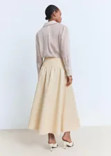 Falda midi evasé de tiro medio en color beige, con cintura entallada y bajo deshilachado.