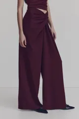 Pantalón de tiro alto color bordó, con corte holgado, piernas rectas y detalle drapeado con nudo girado en la parte frontal.