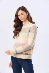 Buzo de tejido de punto con diseño de rayas horizontales en tonos beige, gris y rosado. Presenta cuello redondo, mangas largas y puños con terminación acanalada. Incluye un pequeño parche decorativo de cuero sintético en la parte inferior.