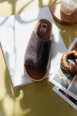 Sandalia marrón de cuero con suela plana.