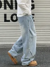 Jean baggy de tiro alto y lavado claro, con diseño amplio, pinzas y efecto desgastado en los muslos.