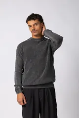 Sweater de punto con textura waffle, cuello redondo y mangas largas. Presenta un diseño de tejido grueso con efecto desgastado en tonos gris oscuro y negro, con puños y ruedo acanalados.