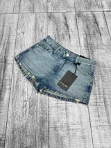 Short de jean tiro bajo color celeste lavado, con roturas sutiles en los bordes y bolsillos delanteros y traseros. Marca Psychic.