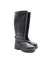 Bota de caña alta color negro, con suela track de plataforma y taco cuadrado. Diseño minimalista con costuras visibles en la puntera.