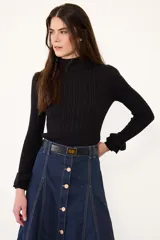 Polera de tejido de punto con diseño acanalado y ochos, cuello alto y mangas largas con terminación de volados en los puños.