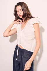 Blusa blanca de algodón con bordado broderie, escote en V con cordón ajustable, mangas cortas con volados y corte al cuerpo.