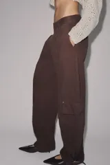 Pantalón cargo de tiro medio confeccionado en algodón, con diseño de pierna tipo barril. Presenta bolsillos laterales y bolsillos de plastrón con solapa en las piernas, además de un bajo ajustable con trabillas y hebilla metálica.