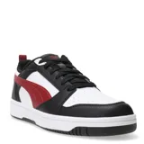 Championes urbanos Puma modelo Rebound V6 Low, con diseño de bloques de color en blanco, negro y rojo. Presentan una parte superior de cuero sintético con perforaciones en la puntera, cierre con cordones y suela de goma blanca con detalle de logo grabado.