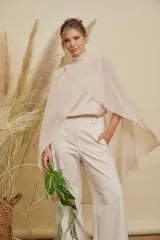 Capa de gasa color beige con cuello alto y diseño cruzado en el frente, de corte fluido y elegante.