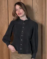 Camisa de jean color negro lavado, con cuello mao con volados, mangas largas abullonadas con puños ajustados y cierre frontal con botones.