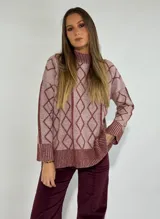 Sweater de lana color rosado con estampado de rombos en bordó. Tiene cuello alto y puños y dobladillo acanalados.