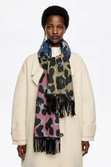 Chal rectangular con diseño de bloques de color y estampado animal print. Presenta flecos en los extremos y etiqueta con logo de la marca en una esquina.