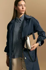 Camisa de manga larga con diseño de rayas verticales en tonos grises y blancos, cuello camisero y cierre frontal con botones.