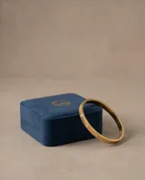Esclava rígida de acero con baño de oro, diseño texturizado y apliques de circonias brillantes.