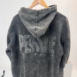 Canguro gris oscuro con efecto lavado, capucha con cordón ajustable y puños elásticos. Estampado en la espalda con la palabra "PEACE" en letras grandes color verde agua y símbolos relacionados con la paz.