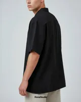 Camisa negra de manga corta en tela liviana y fresca, con corte fit boxy y calce relajado.