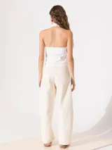 Top blanco de punto con cuello halter cruzado y broche snap en la espalda.