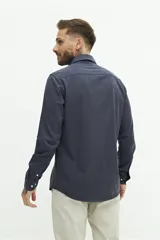 Camisa de manga larga lisa con cuello clásico y cierre frontal de botones. Presenta un ajuste regular y un pequeño logo bordado en el pecho.