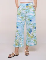 Pantalón crop de lino y rayón, con diseño wide leg de corte holgado, estampado tropical de hojas en tonos verde, azul y marrón sobre fondo blanco. Cuenta con pretina trasera elastizada y bolsillos delanteros.