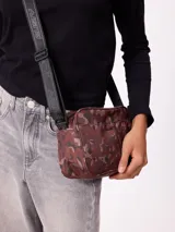 Bolso tipo morral de la marca Rusty, con diseño estampado camuflado en tonos marrones. Cuenta con correa ajustable y cierre frontal con logo de la marca.