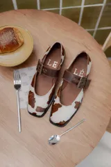 Zapatos tipo Mary Jane color marrón con hebilla dorada y punta cuadrada.