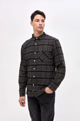 Camisa de manga larga con cuello clásico y cierre frontal de botones. Presenta un diseño a cuadros en tonos oscuros, con un bolsillo en el pecho que incluye un pequeño bordado de la marca.