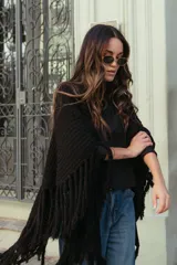 Poncho triangular de lana en color crudo, con diseño de tejido texturizado y terminaciones de flecos largos en todo el borde.