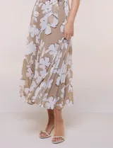 Vestido maxi sin mangas de gasa plisada, color beige con estampado floral blanco. Presenta escote redondo fruncido, falda evasé y lazo para anudar en la cintura.