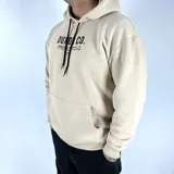 Canguro color tostado con capucha, corte oversize y estampado en la espalda con la leyenda "DUXON CO.", texto en japonés y "TOKYO".