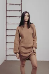 Vestido corto de tejido de punto color tostado, con cuello alto, mangas largas amplias y diseño ajustado al cuerpo.