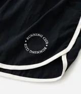 Short deportivo modelo runner de Ashua, confeccionado en poliamida con tecnología dry de secado rápido. Presenta un diseño holgado con cintura elástica, bajos redondeados con vivos laterales en contraste y detalle de lettering en el ruedo.